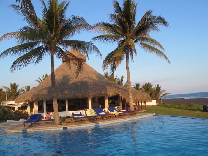Hotel mit Strohdach, Palmen und Pool am Meer
